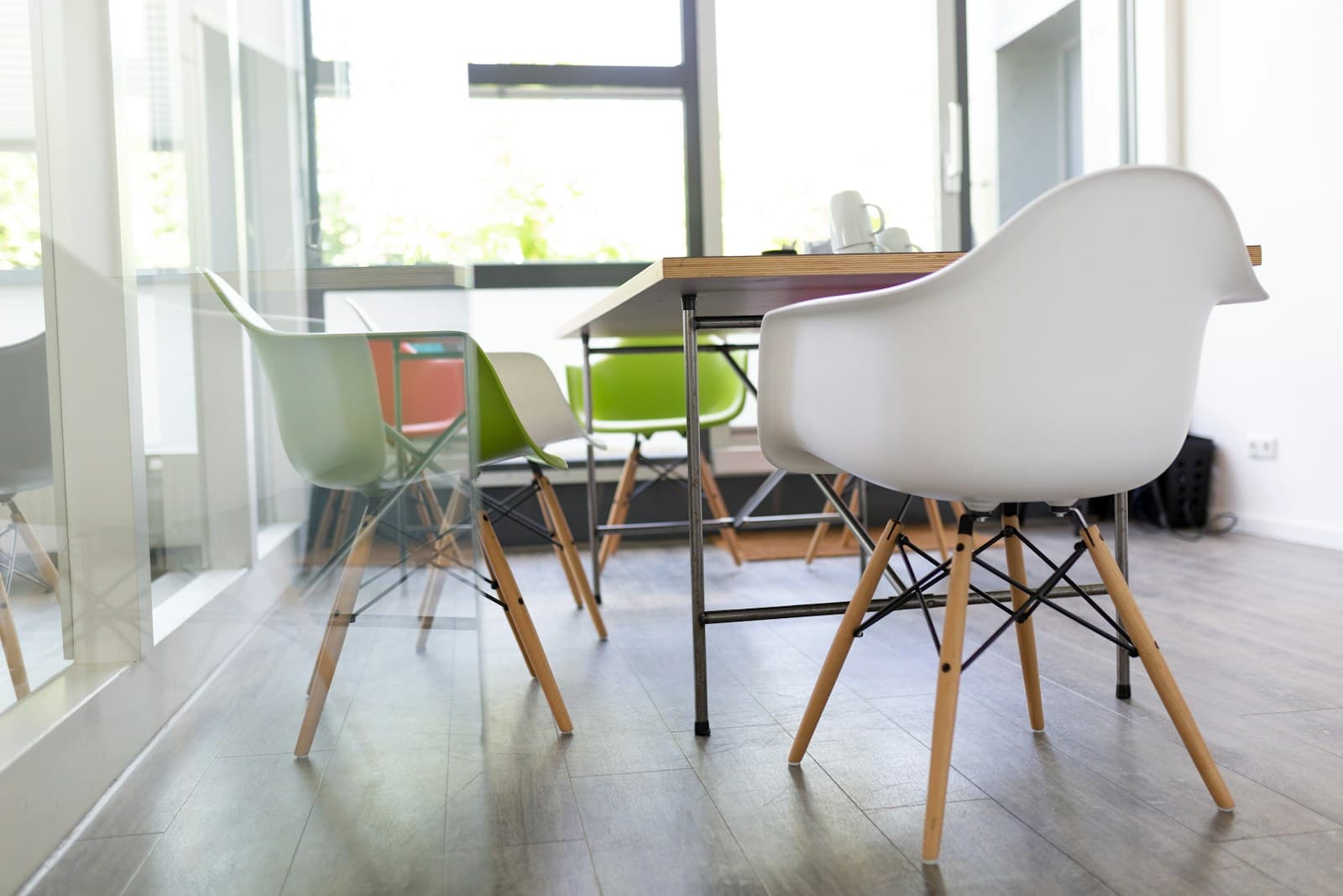 Bright meeting room with white walls, a wooden table and colourful chairs