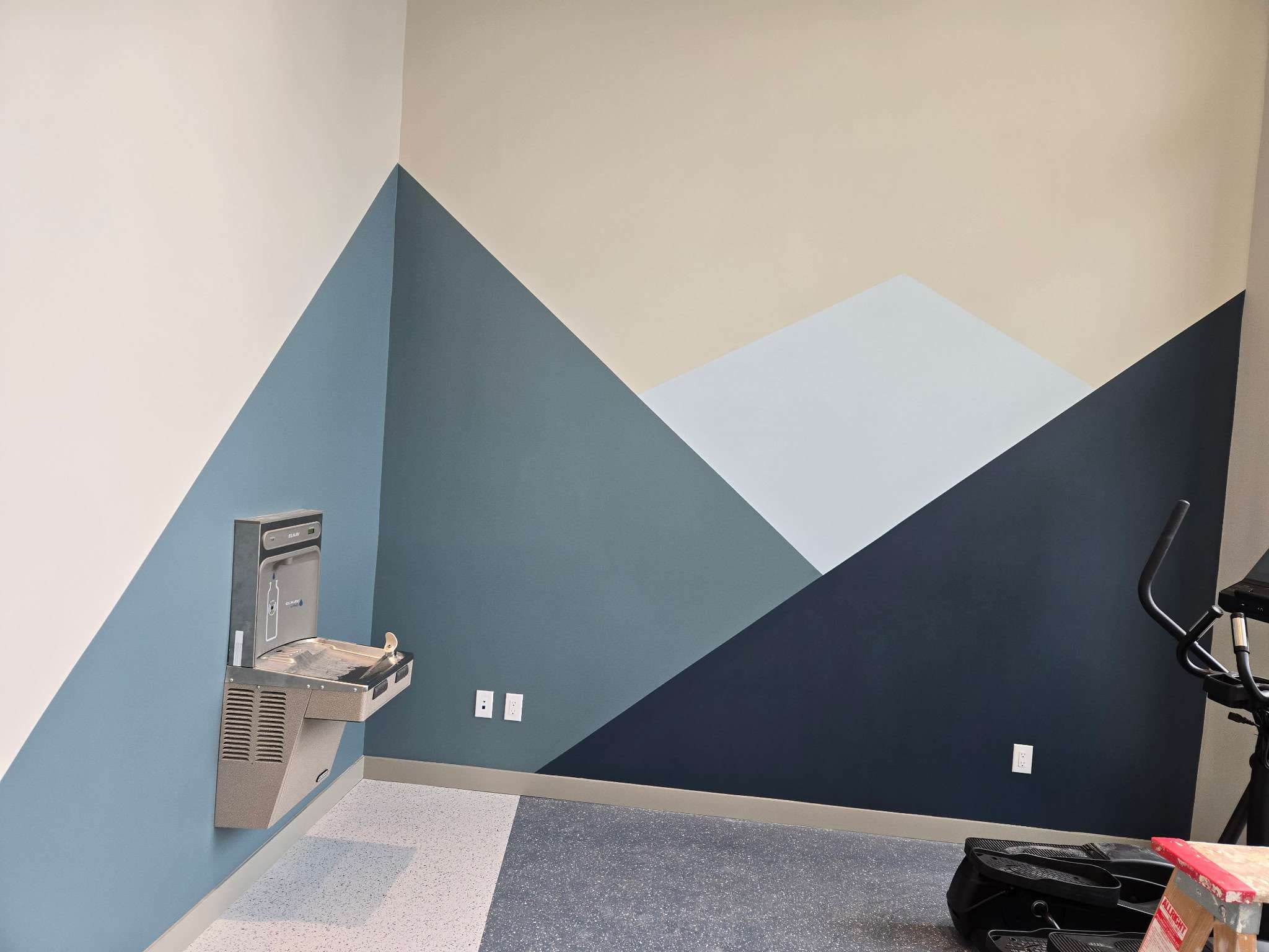 Geometric blue and grey mountain shapes painted around an amenity-room corner